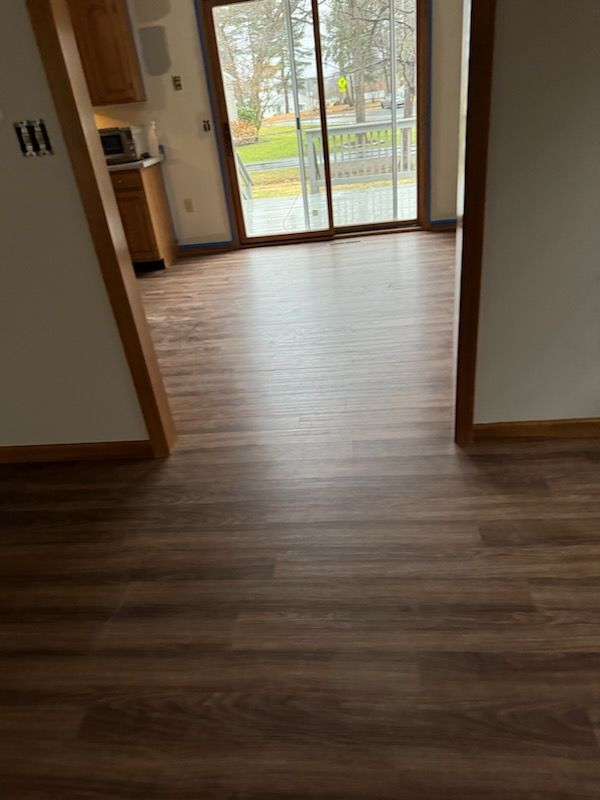 A living room with hardwood floors and a sliding glass door leading to a balcony.