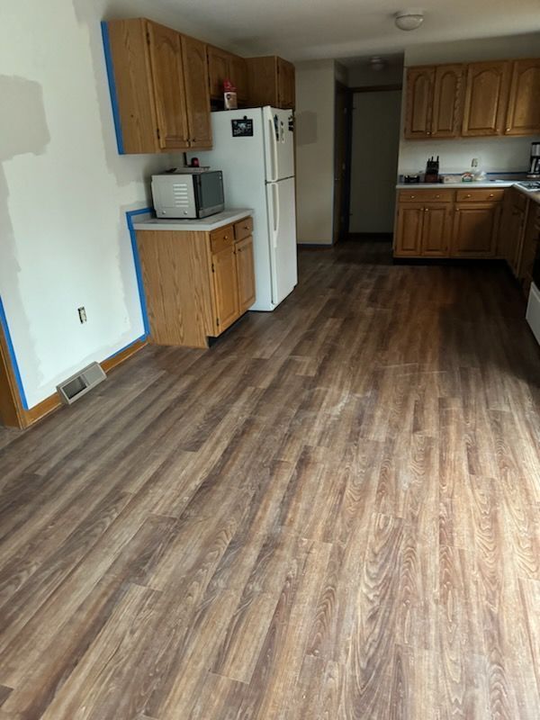 A kitchen with hardwood floors and wooden cabinets