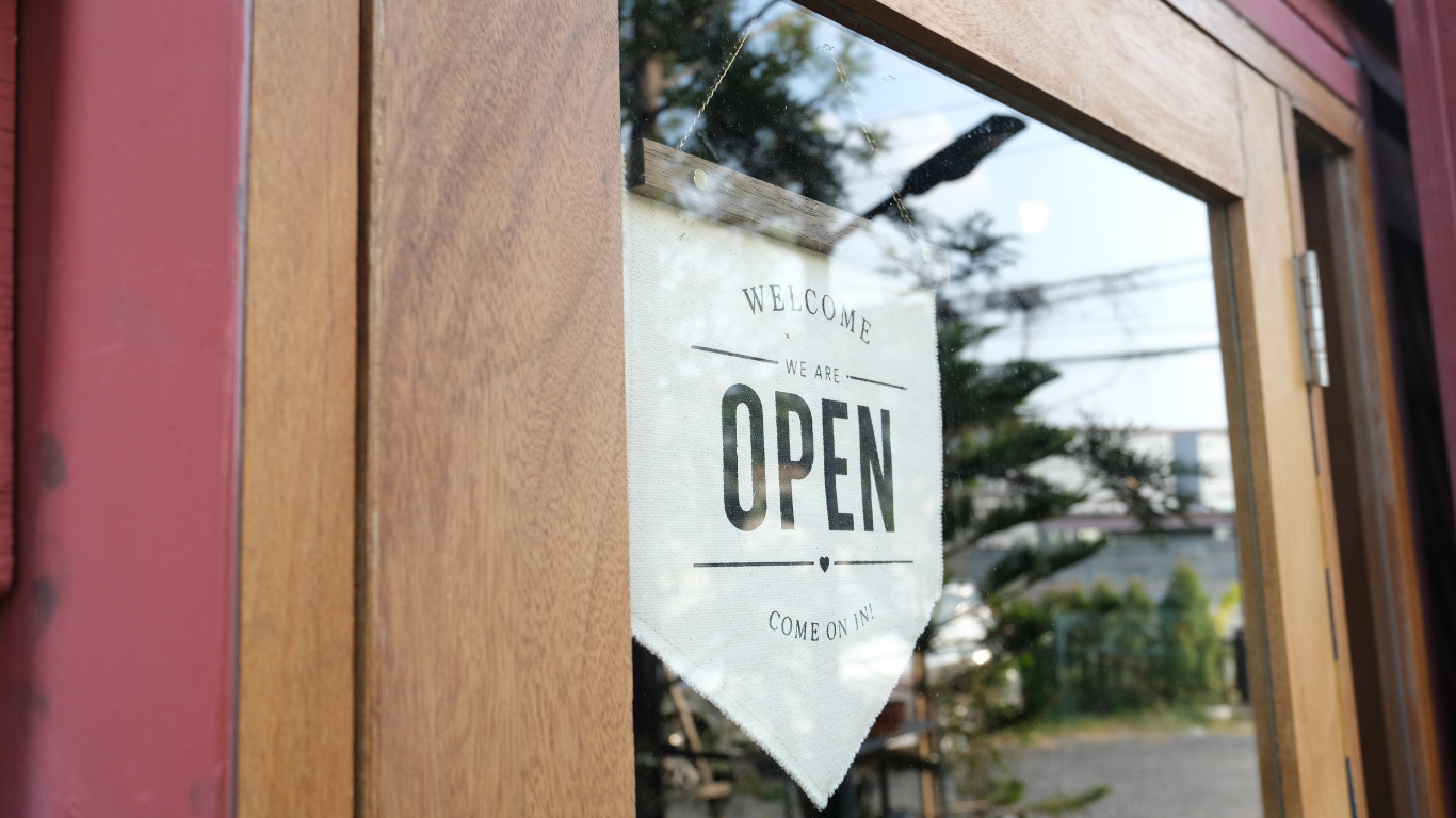 A close up of an open sign on a glass door.