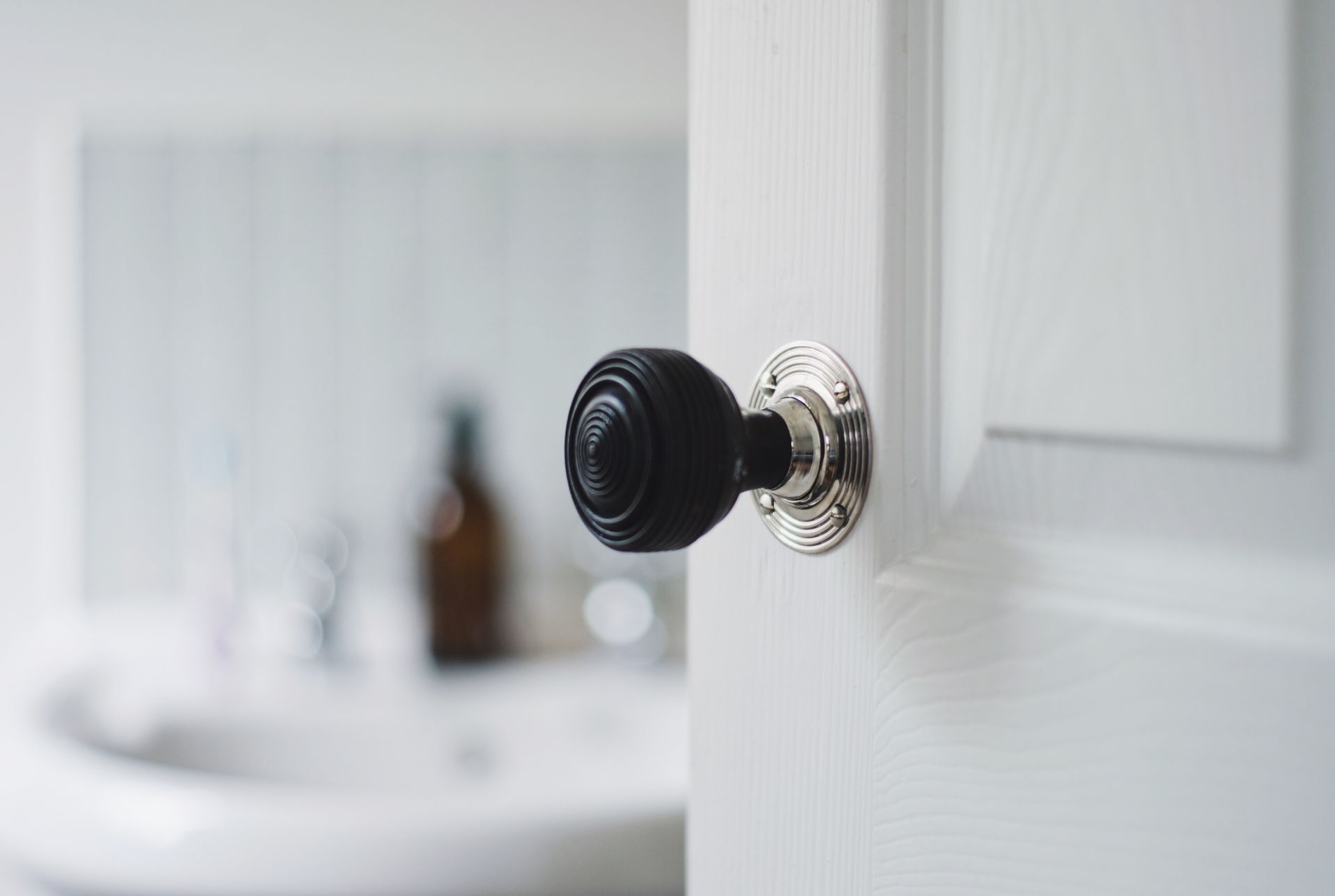 A close up of a door with a black door knob in a bathroom. A close up of a door with a black door knob in a bathroom.