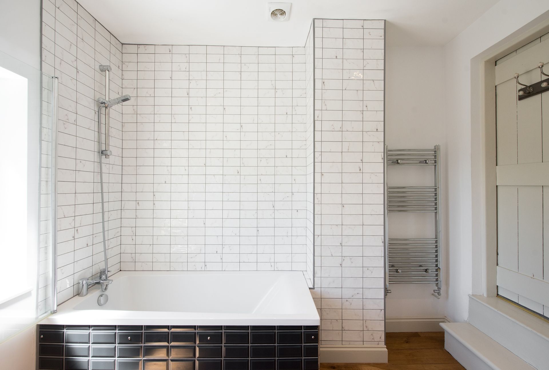 A bathroom with black and white tiles and a bathtub. A bathroom with black and white tiles and a bathtub.