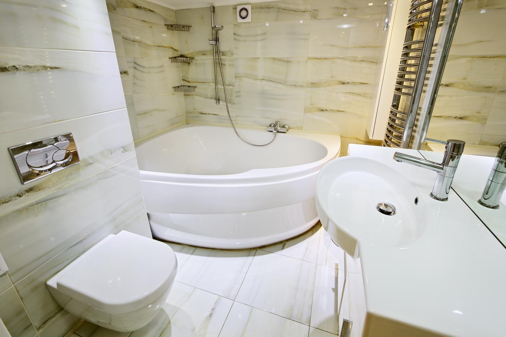 A bathroom with a tub , sink , toilet and mirror.