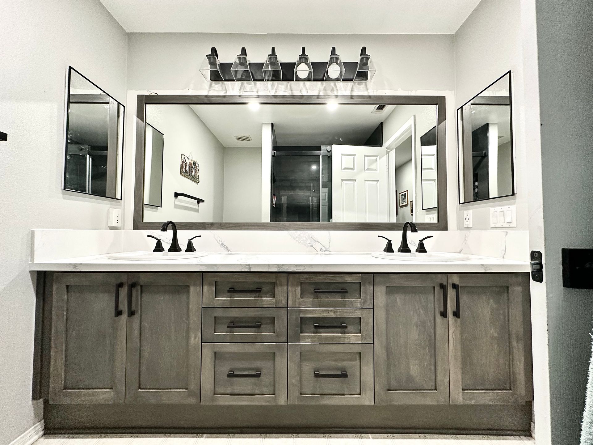 Double bathroom vanity with a large mirror, dual sinks, dark wood cabinets, and modern lighting in a neutral-toned room.
