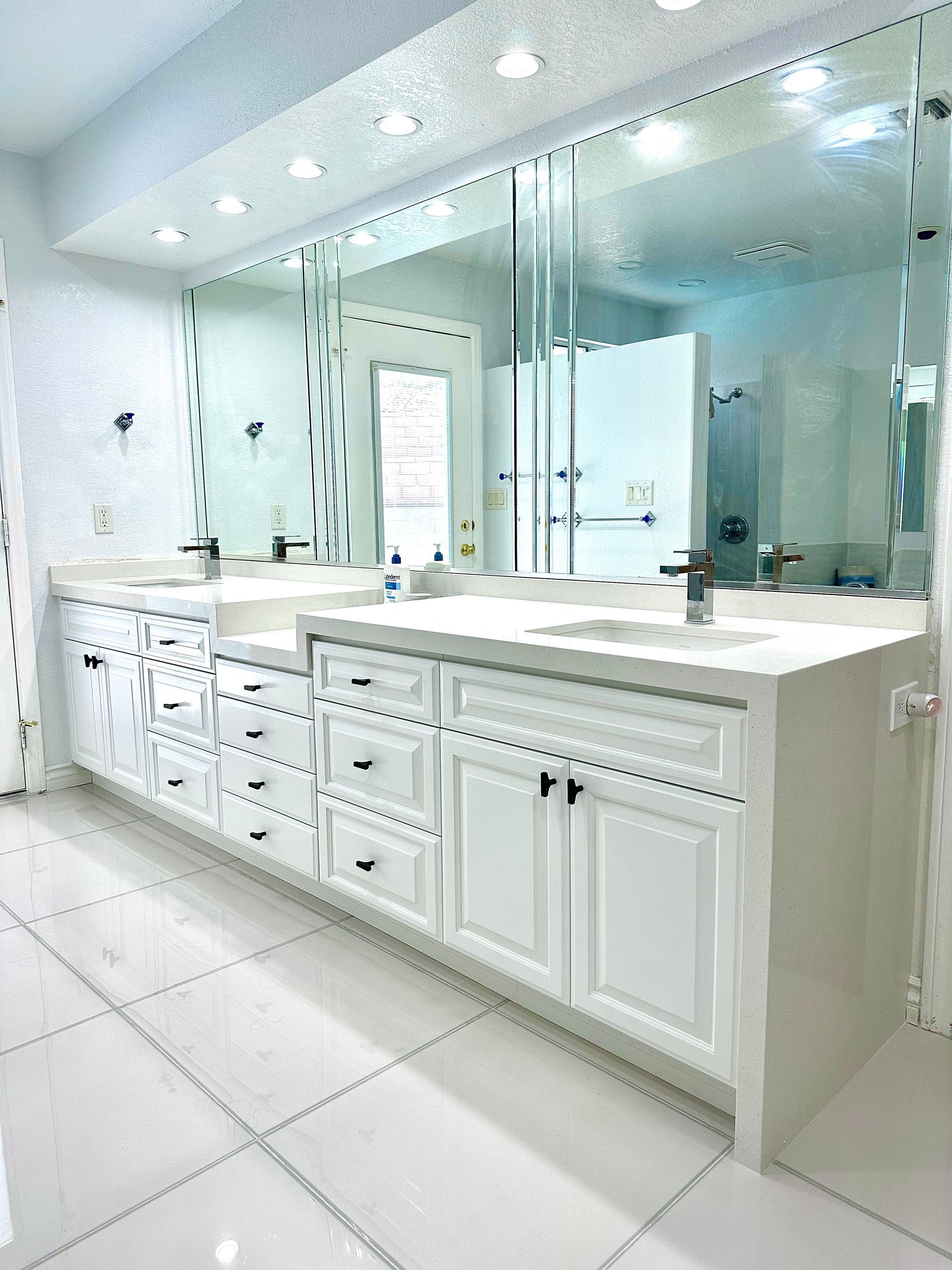 A long white double-sink bathroom vanity with drawers and cabinets.