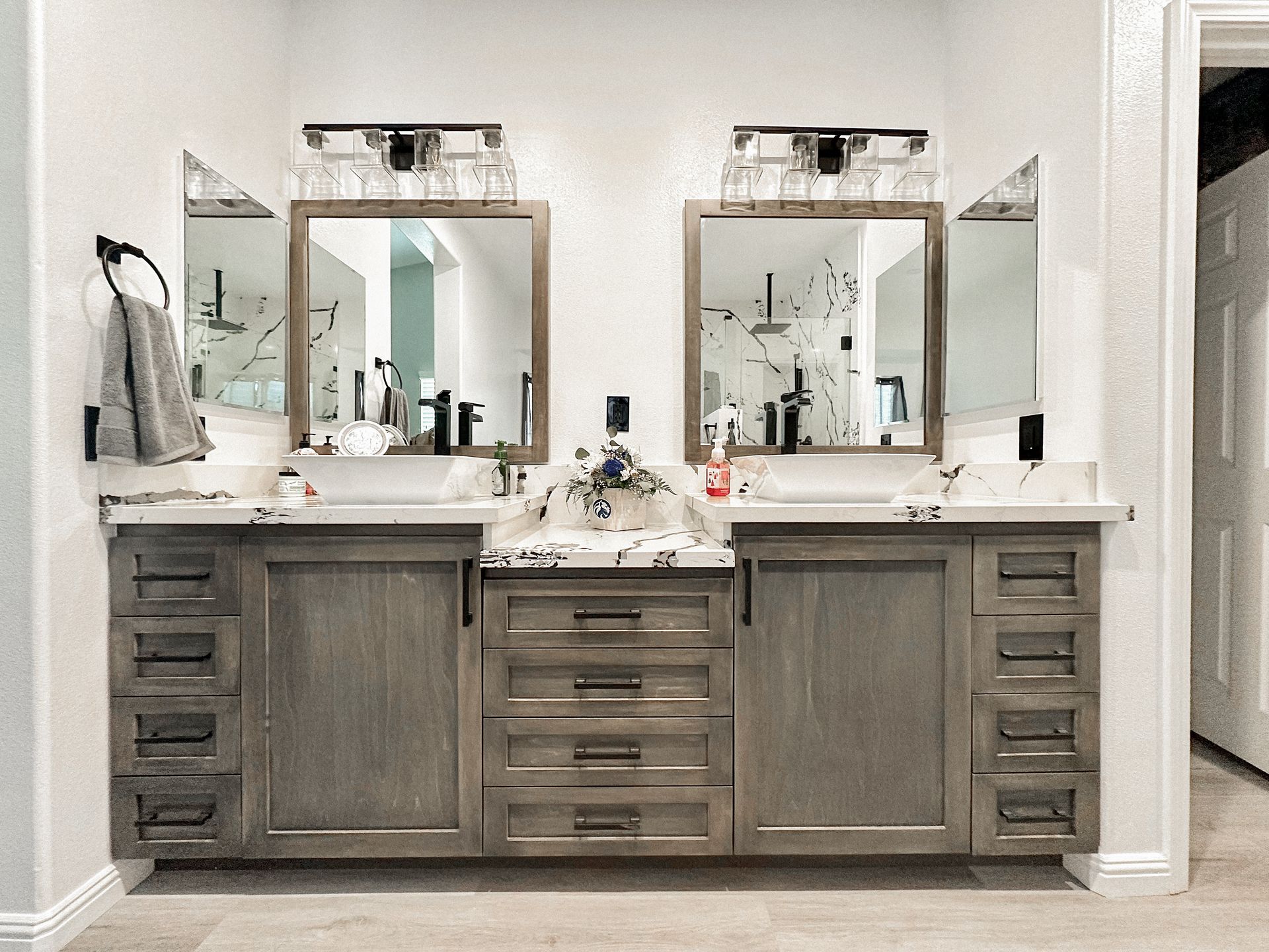 A double vanity with a marble countertop, light wood cabinets, two rectangular mirrors, and silver light fixtures.