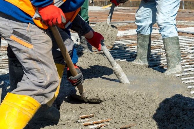 Workers pouring concrete into a sidewalk form at a construction site