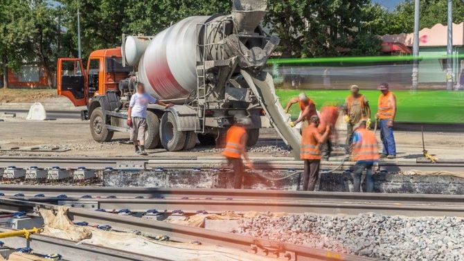 Workers pour molten metal from a truck onto train tracks during rail repair.