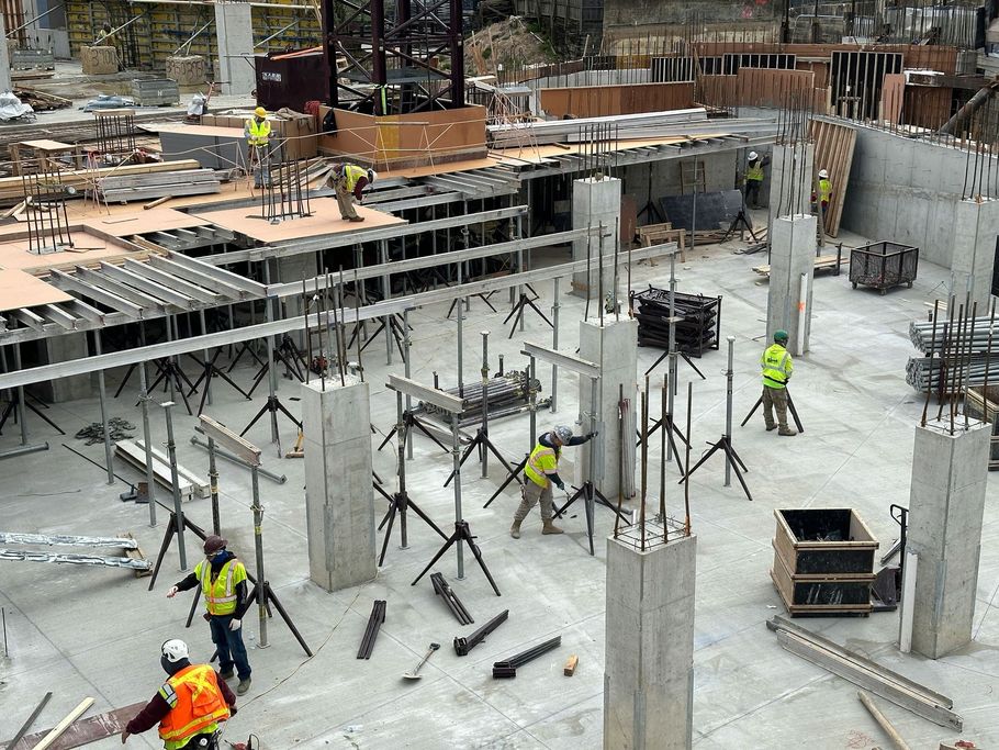 Construction workers pouring concrete on a building site with columns and scaffolding