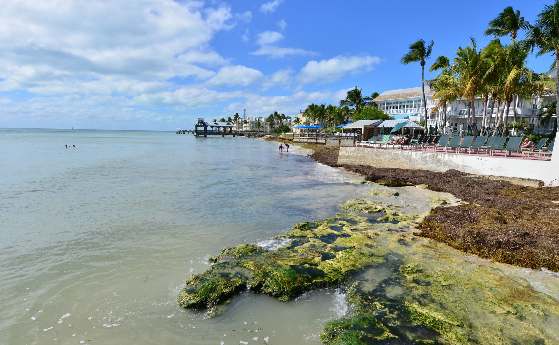 Life preserver ring, white with red stripes, hangs on a metal railing against a clear blue sky.