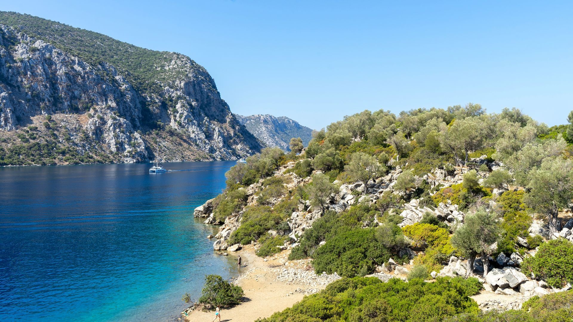 Life preserver ring, white with red stripes, hangs on a metal railing against a clear blue sky.