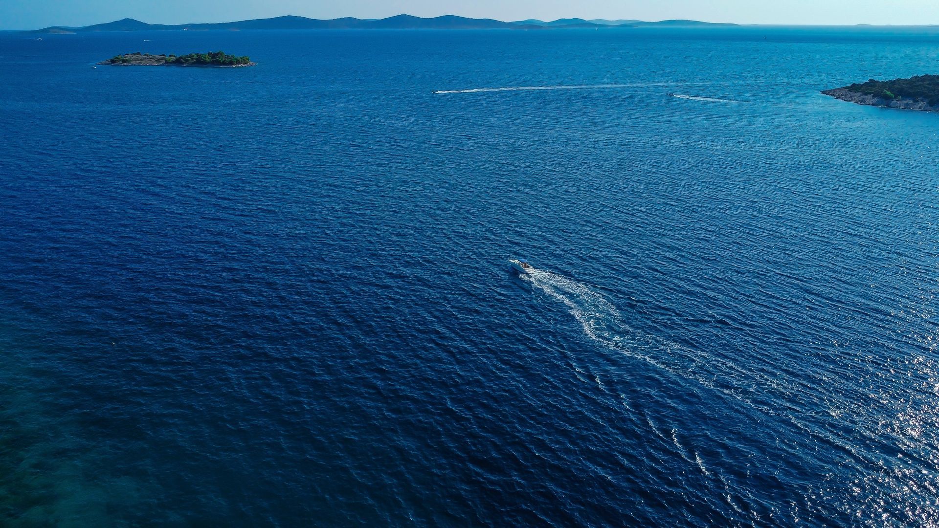 Life preserver ring, white with red stripes, hangs on a metal railing against a clear blue sky.