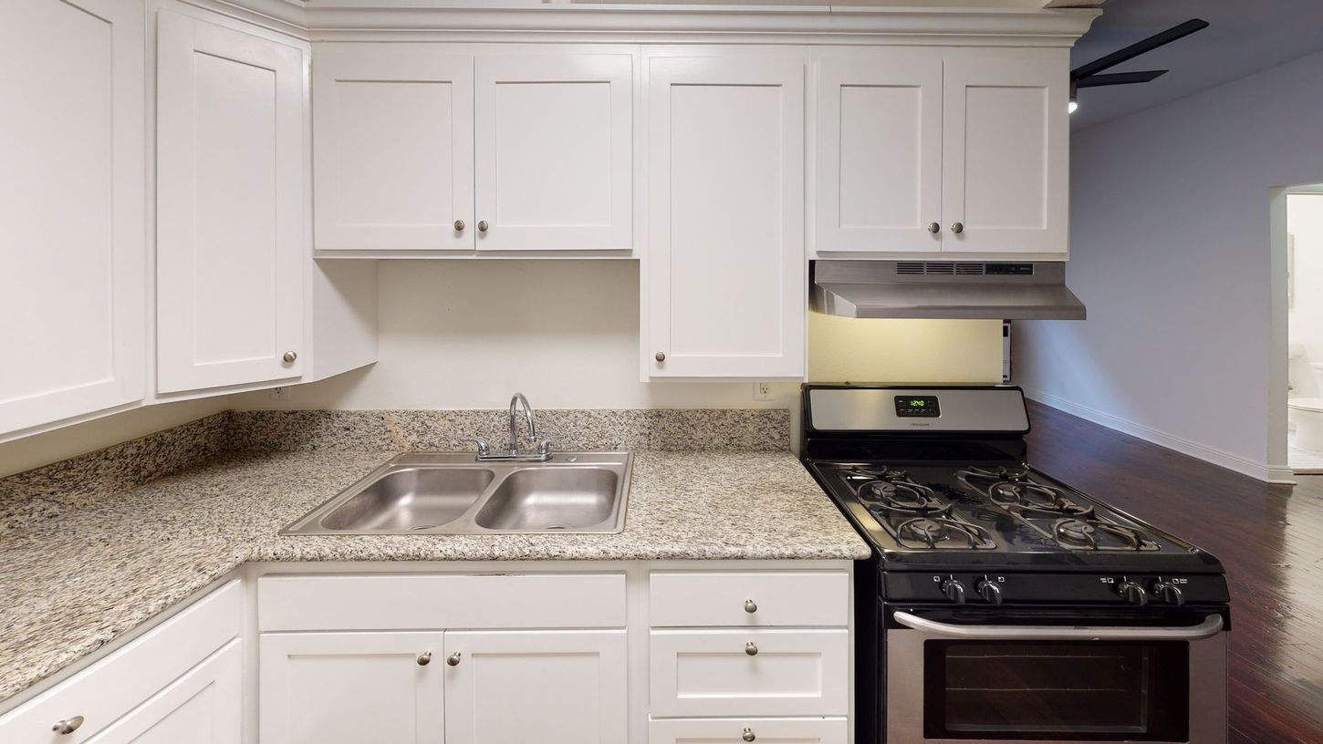 White kitchen with granite countertops, stainless steel sink and appliances.