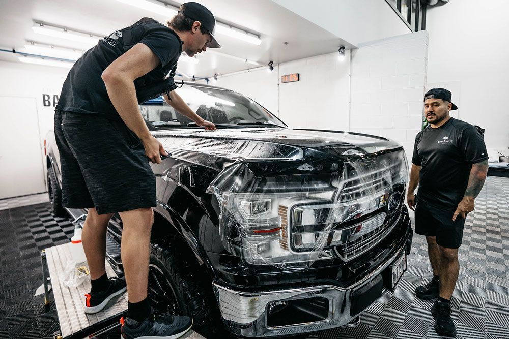 Two men are working on a truck in a garage.