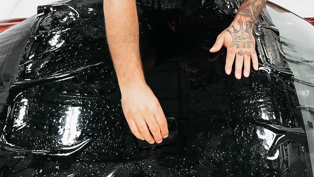 A man is installing black PPF