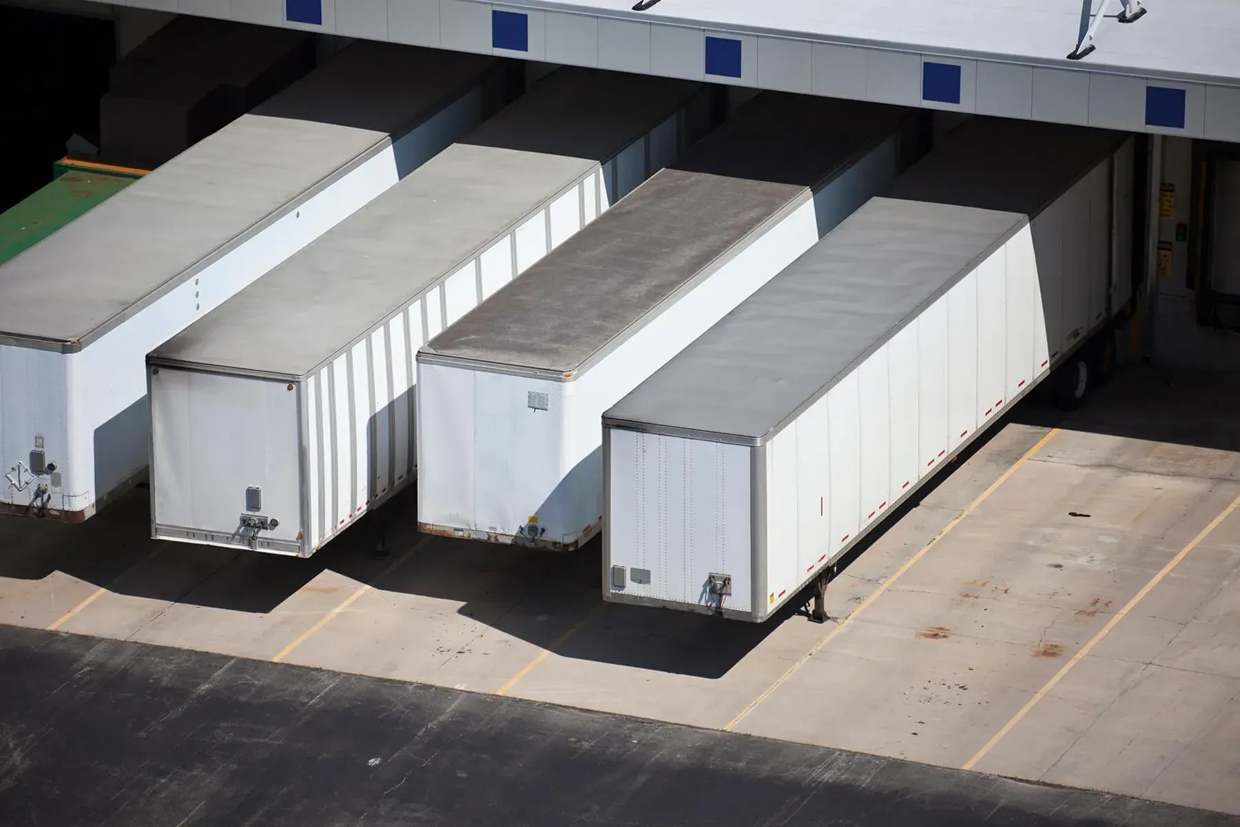 A row of semi trucks are parked in a parking lot.