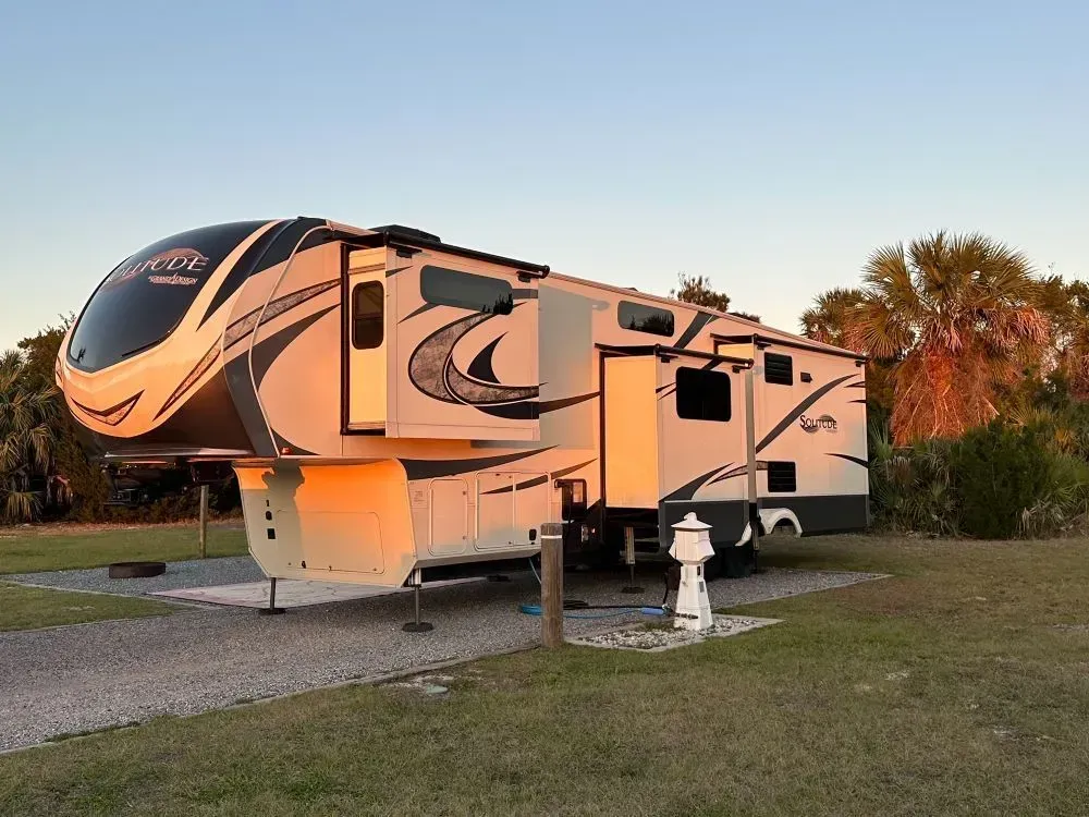A large rv is parked in a grassy field.
