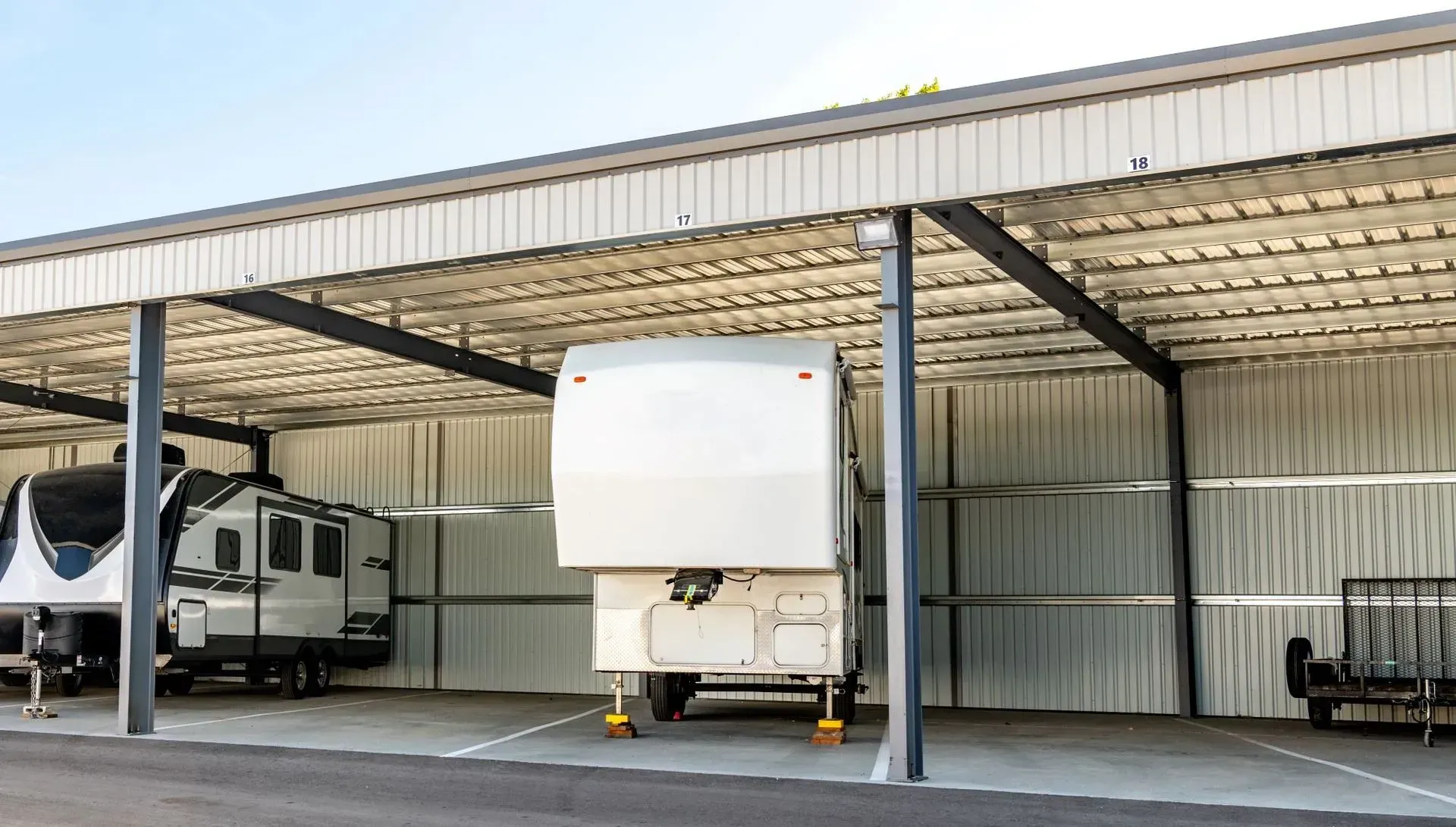 A rv is parked under a canopy in a garage.