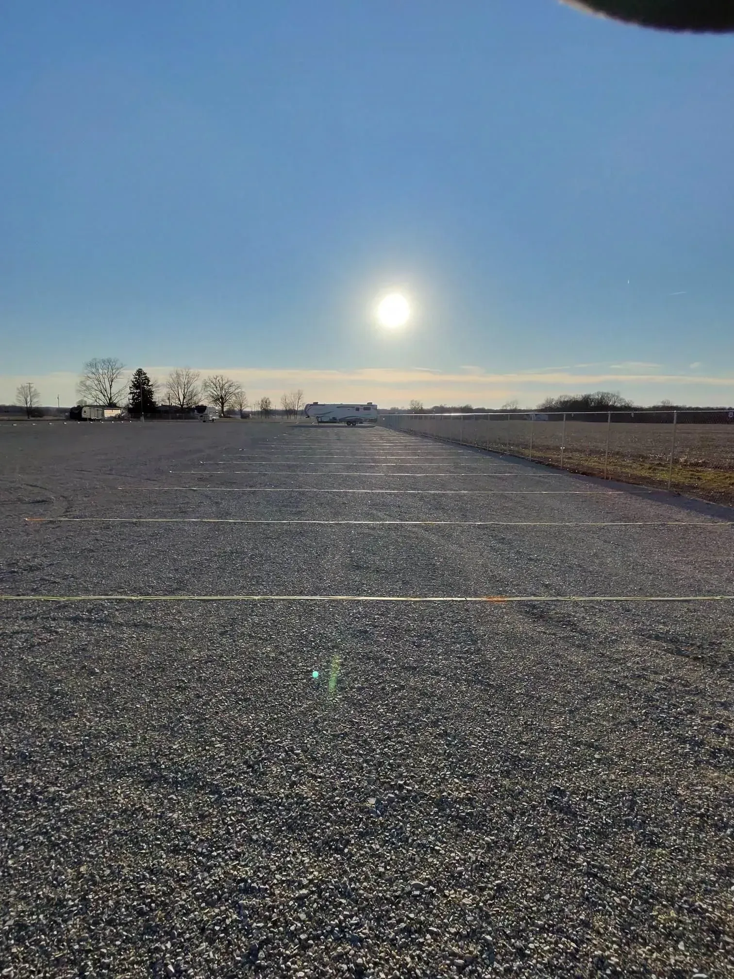 Wide gravel storage lanes with parked RV under a bright, sunny sky.