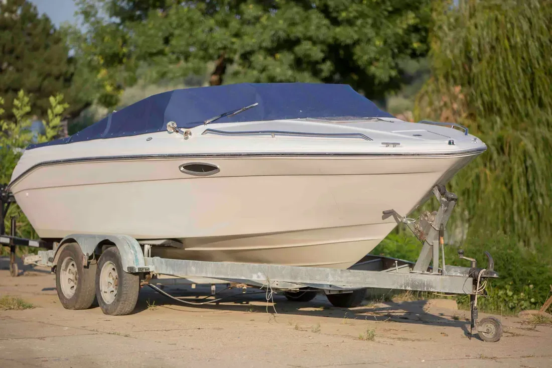 A white boat is parked on a trailer.