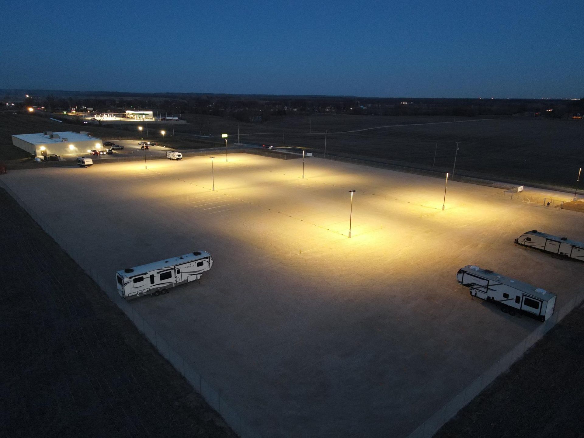 RV parking lot illuminated at night; several RVs parked.