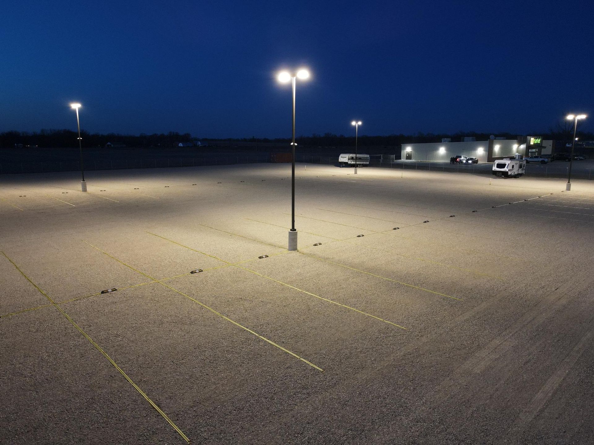 Nighttime parking lot illuminated by tall street lights.
