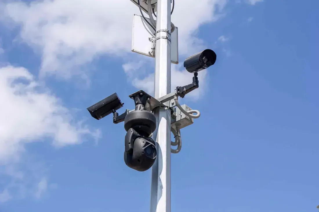 A bunch of security cameras are sitting on top of a pole.