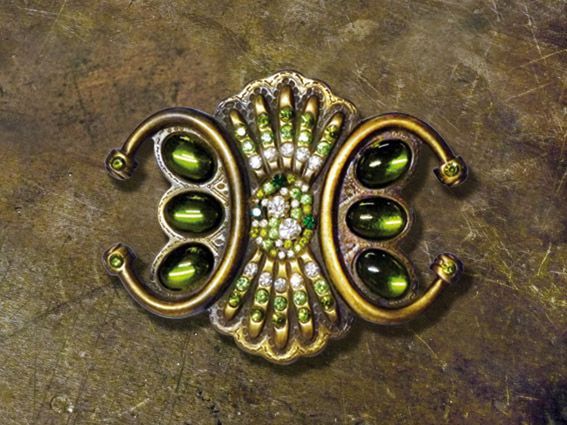 Primo piano di una spilla con perline verdi e strass