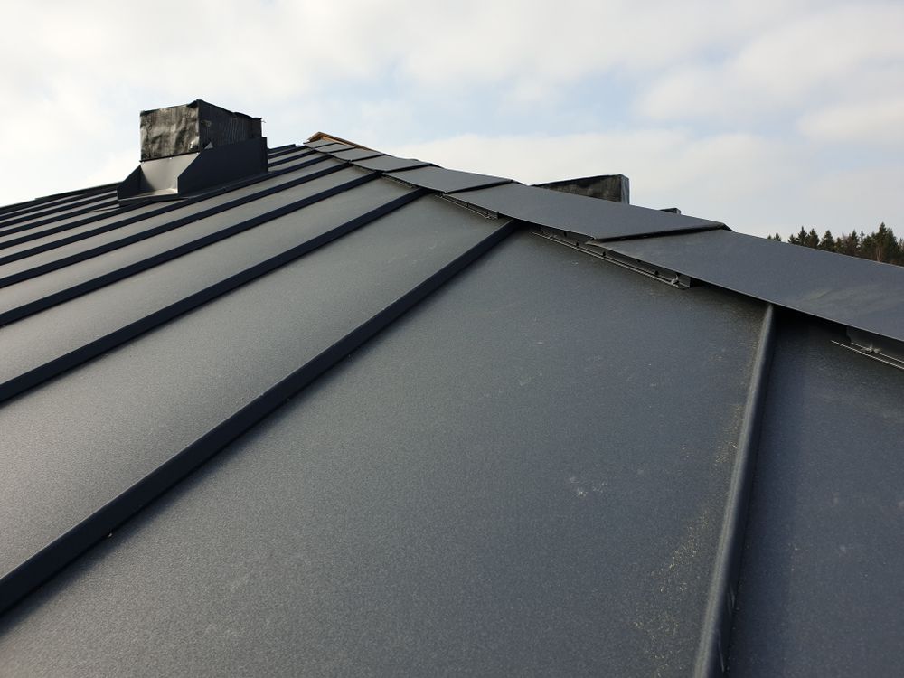 Dark Gray Metal Roof With a Chimney Against a Cloudy Sky — MJD Roofing Sunshine Coast in Cooroy, QLD
