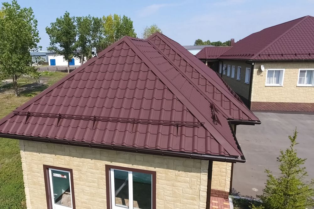 Brown Metal Roof on a Tan Brick Building. Windows, Trees, and Blue Sky — MJD Roofing Sunshine Coast in Cooroy, QLD