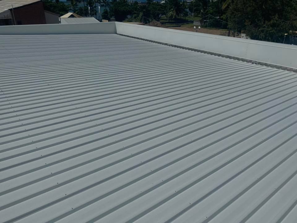 Gray Corrugated Metal Roof With a White Parapet and Residential Setting — MJD Roofing Sunshine Coast in Cooroy, QLD