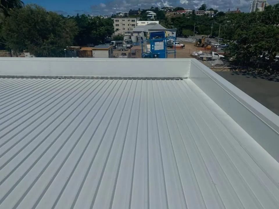 White Corrugated Metal Roof With Building and Construction in the Background — MJD Roofing Sunshine Coast in Cooroy, QLD
