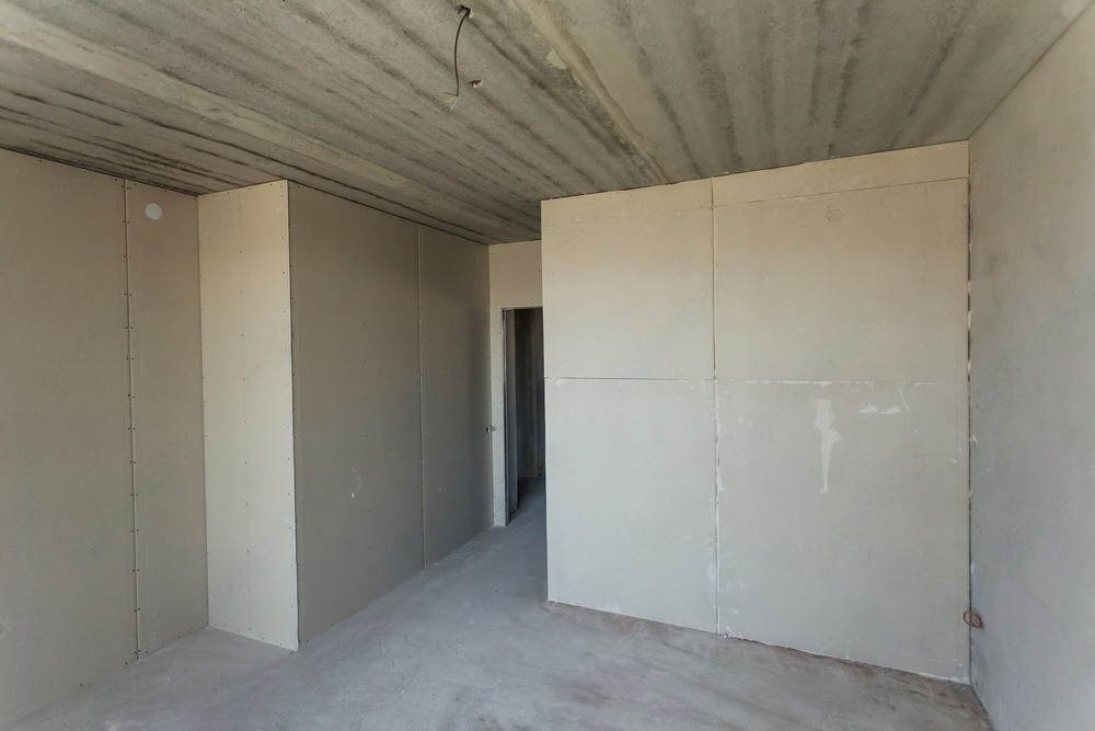 an empty room with white walls and a concrete ceiling .