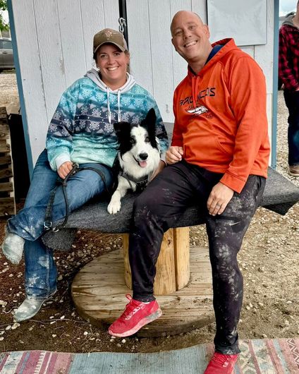 A man and a woman are sitting on a bench with a dog.