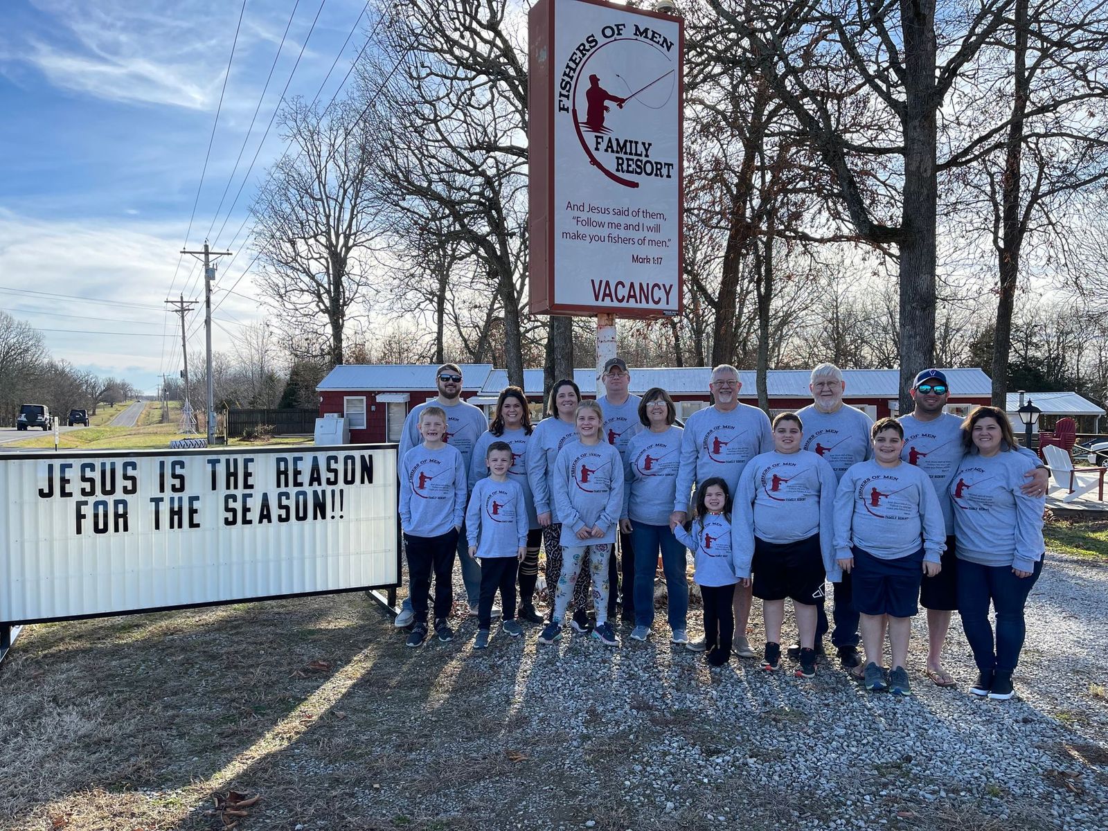 A group of people standing in front of a sign that says jesus is the reason for the season