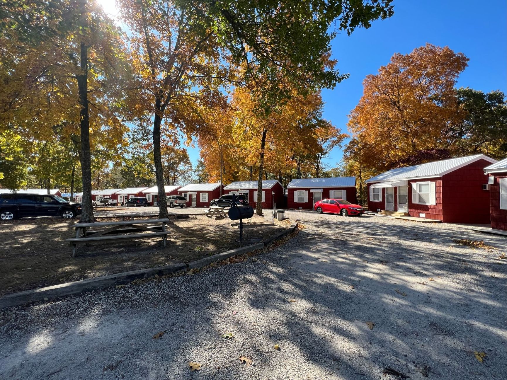 A red car is parked in front of a row of red houses.