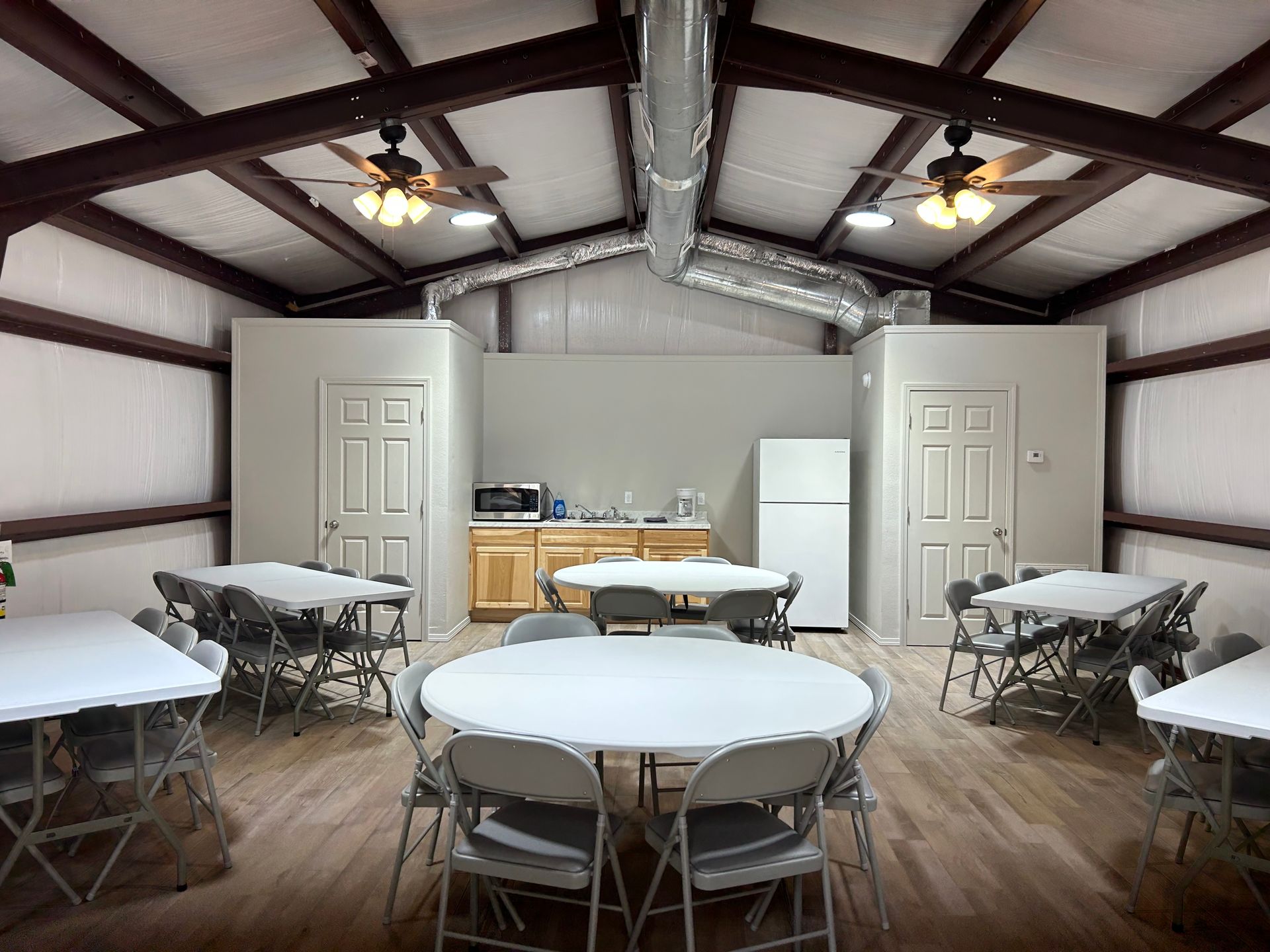 A large room with tables and chairs and a refrigerator.