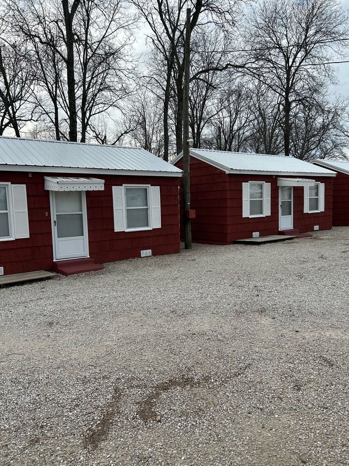 A row of red cabins sitting next to each other in a gravel lot.