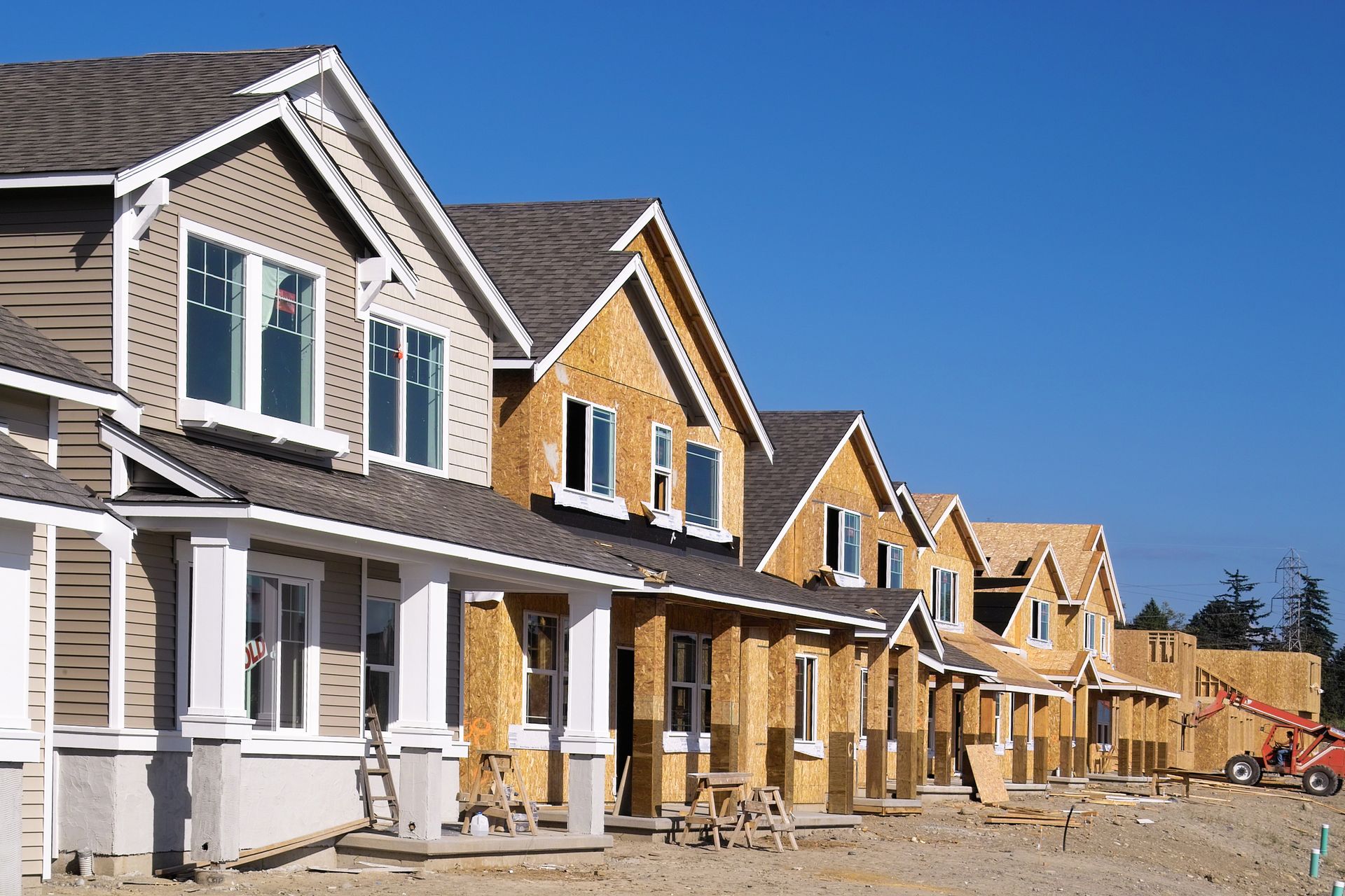 Row of houses under construction with blue sky background.