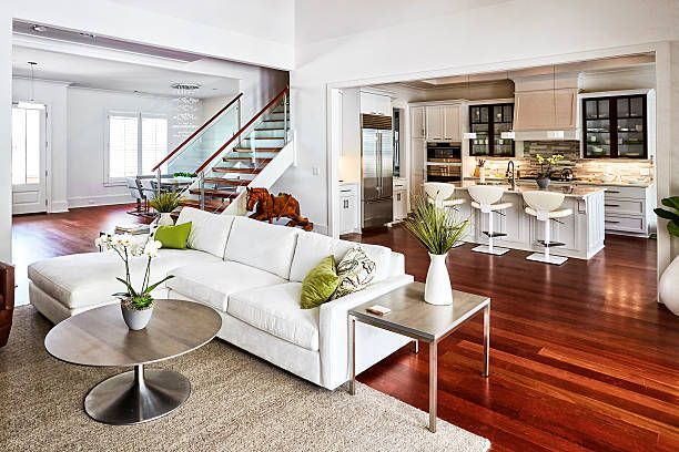 Modern living room with white sofa, hardwood floors, and open kitchen.