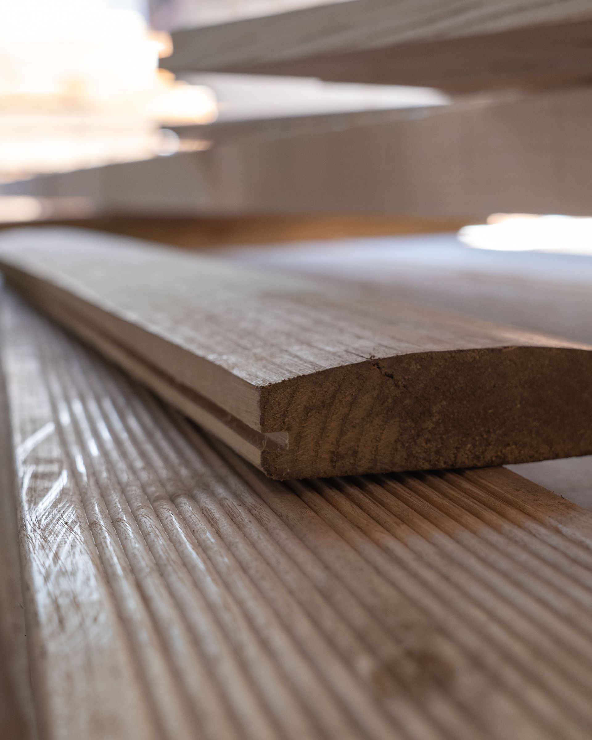 Primo piano di assi di legno impilate orizzontalmente, alcune con bordi arrotondati e scanalature.