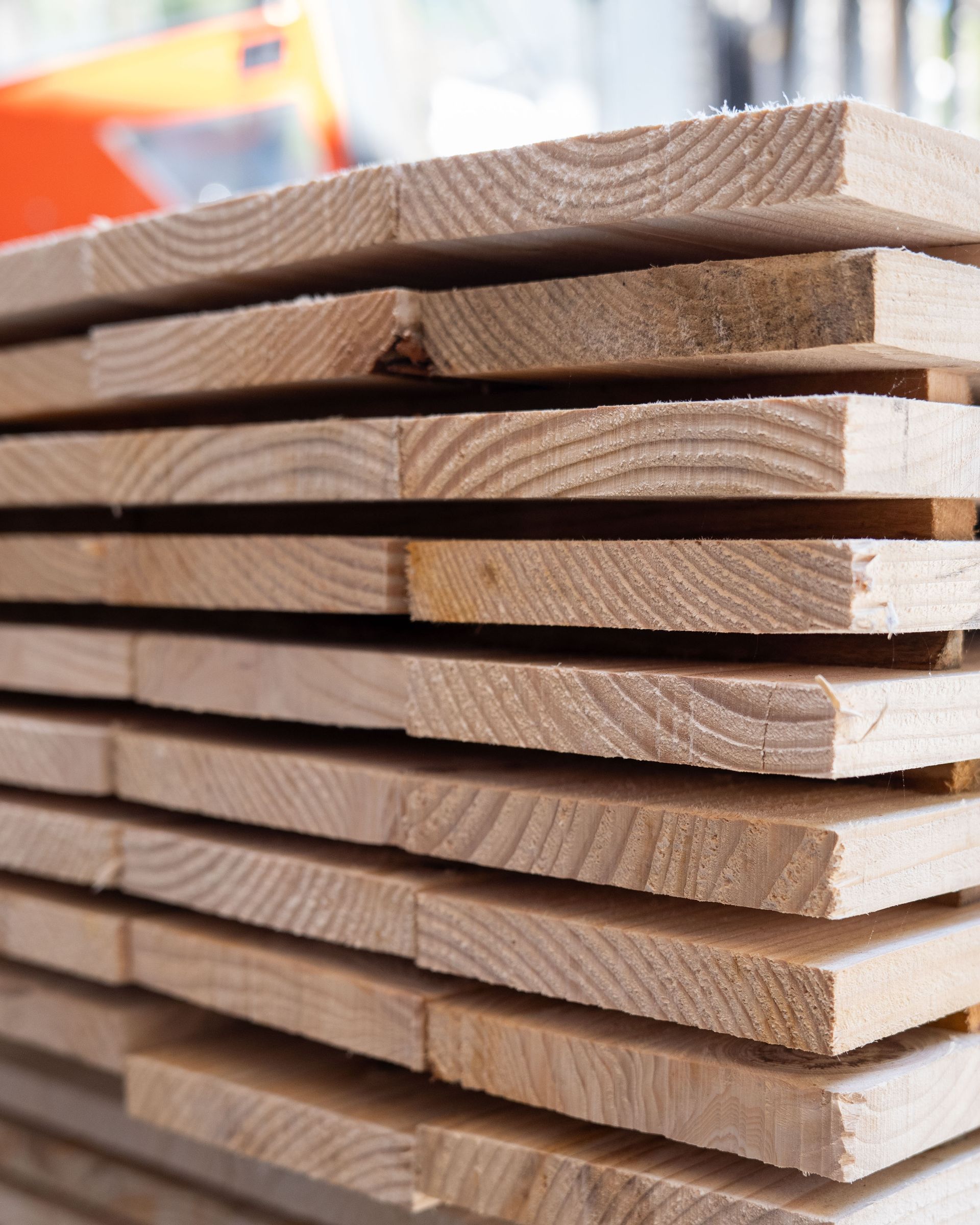Pila di assi di legno chiaro, che mostrano le venature del legno.