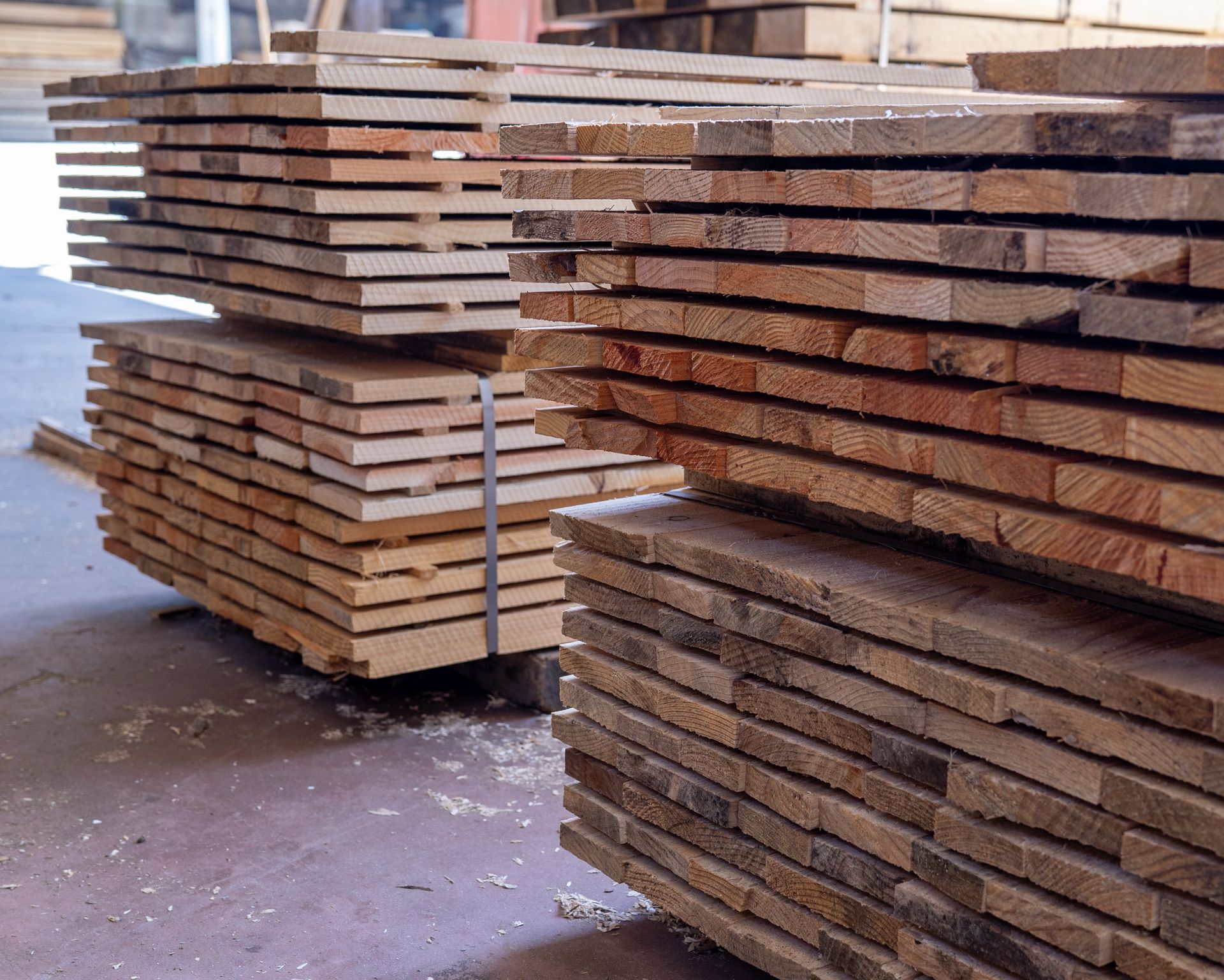 Cataste di legname stagionato in un magazzino, alcune legate insieme.