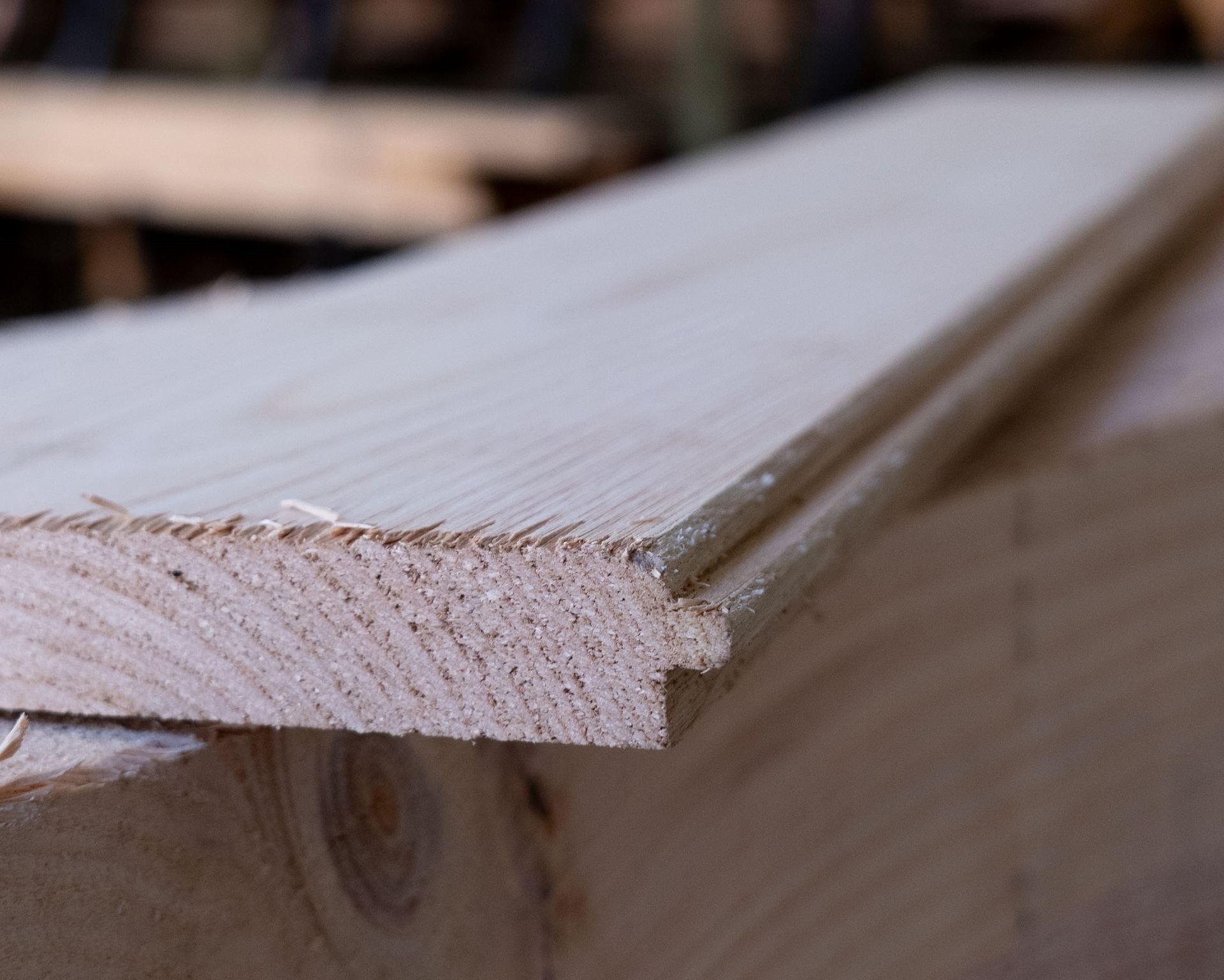 Primo piano di assi di legno grezze con bordo maschio e femmina, probabilmente destinate all'edilizia.