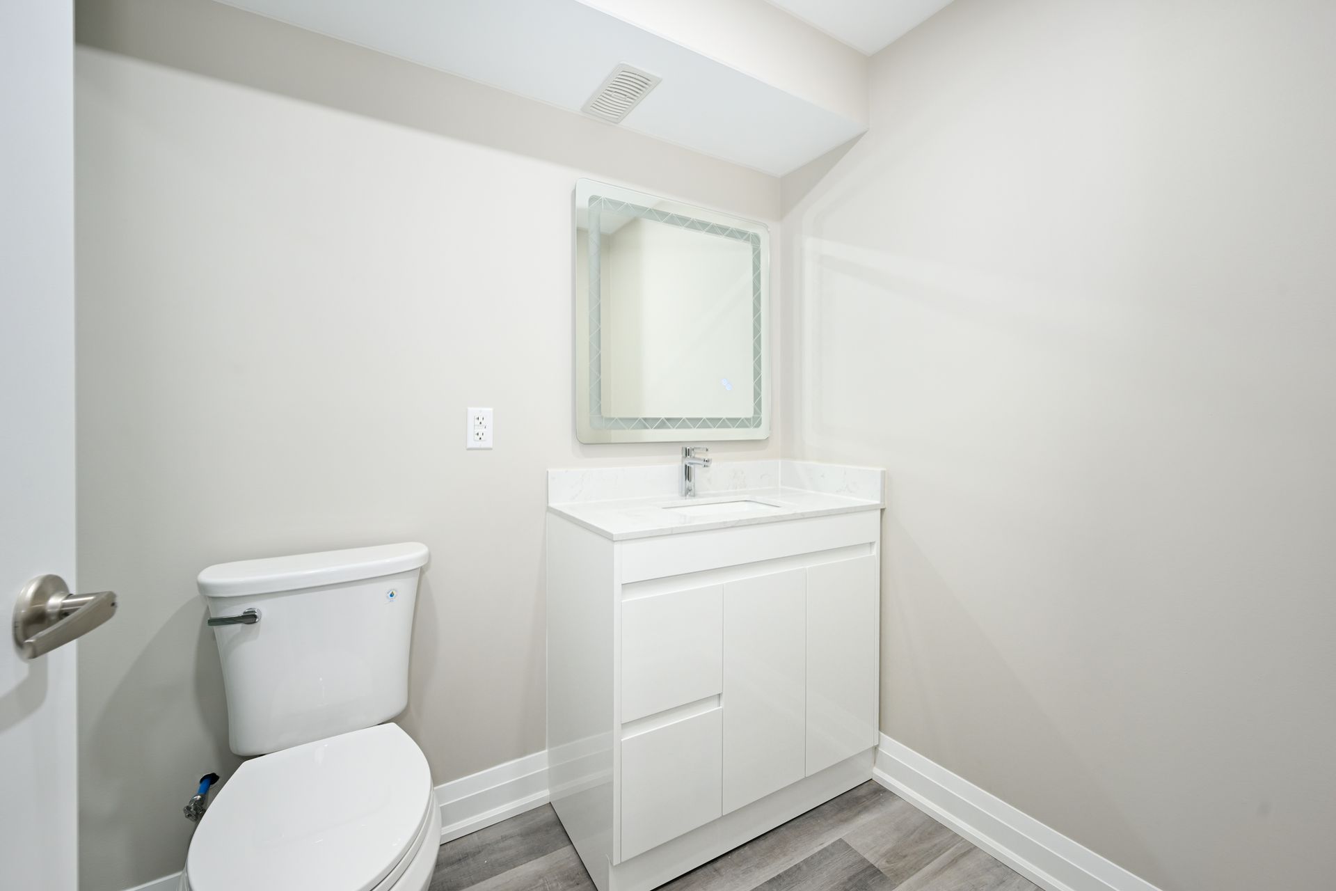 A bathroom with a toilet , sink and mirror.