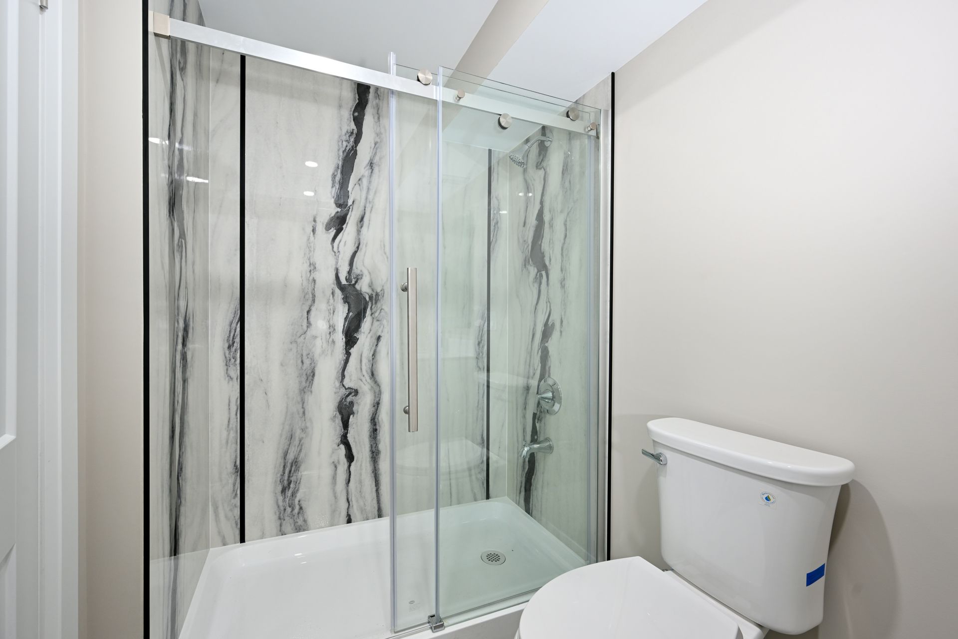 A bathroom with a toilet and a shower with a glass door.