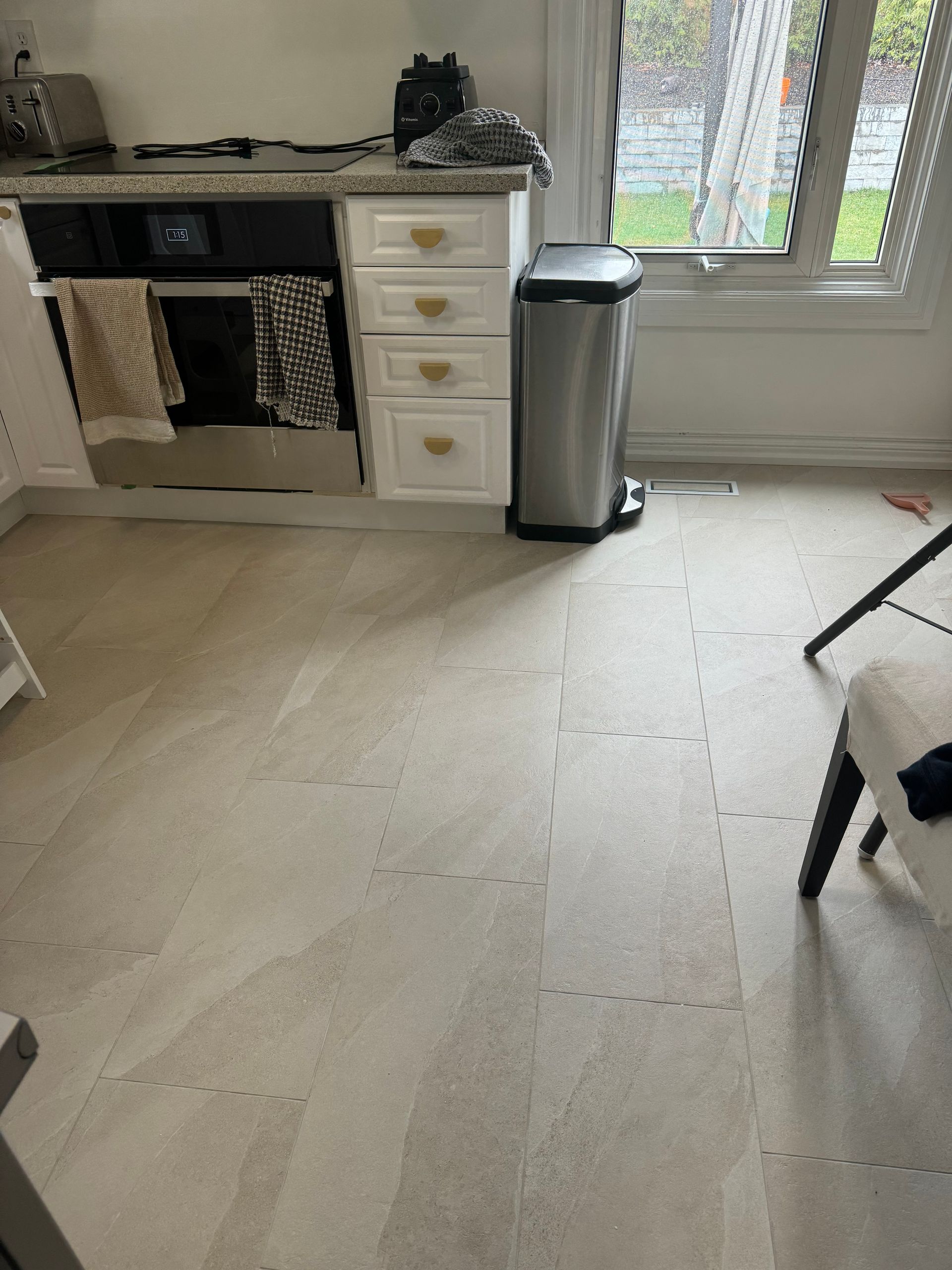 A kitchen with a stainless steel trash can on the floor