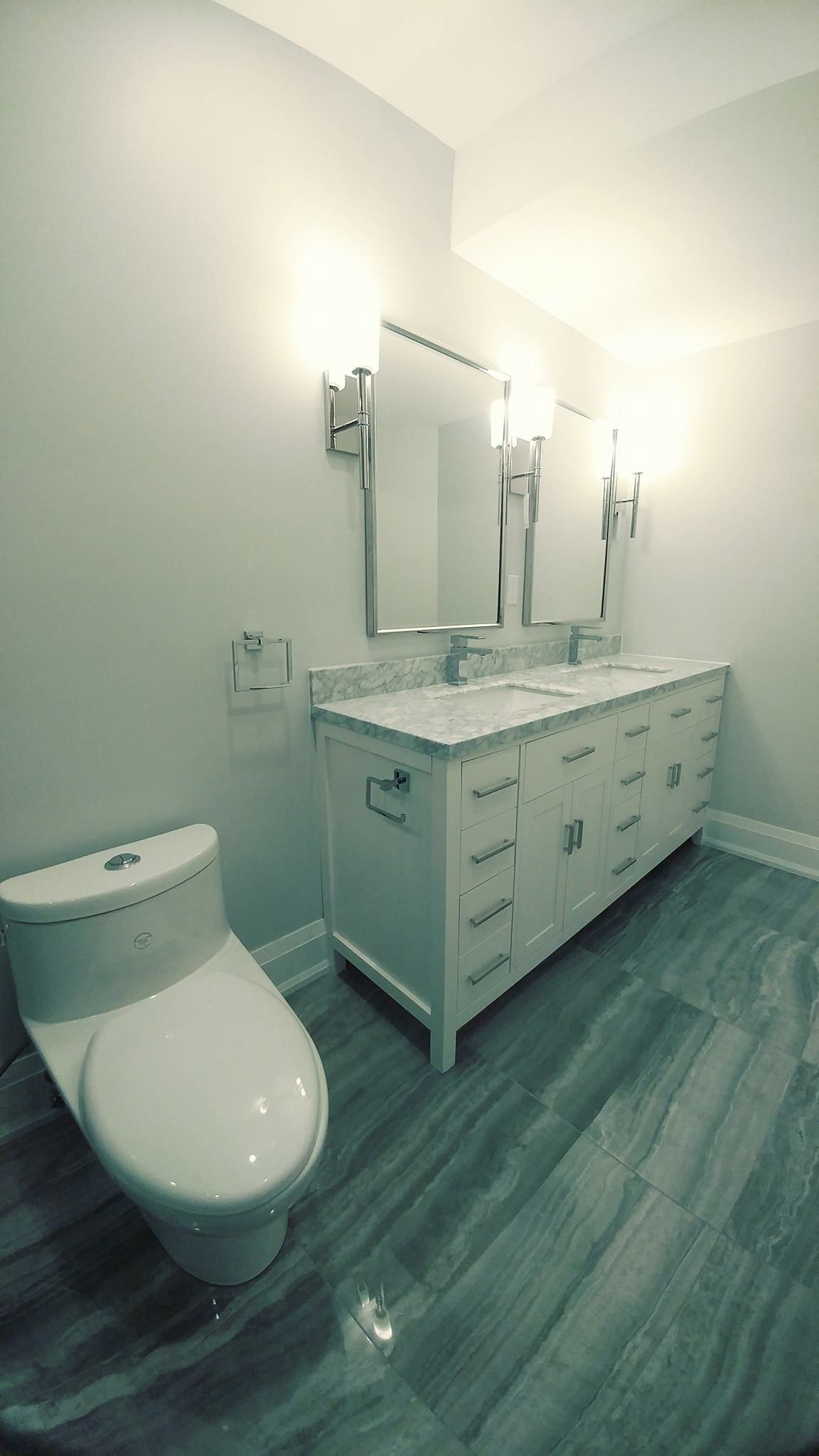 A bathroom with two sinks , a toilet and a mirror.