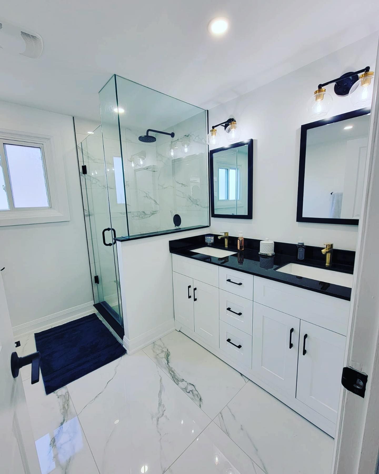 A bathroom with two sinks and a walk in shower