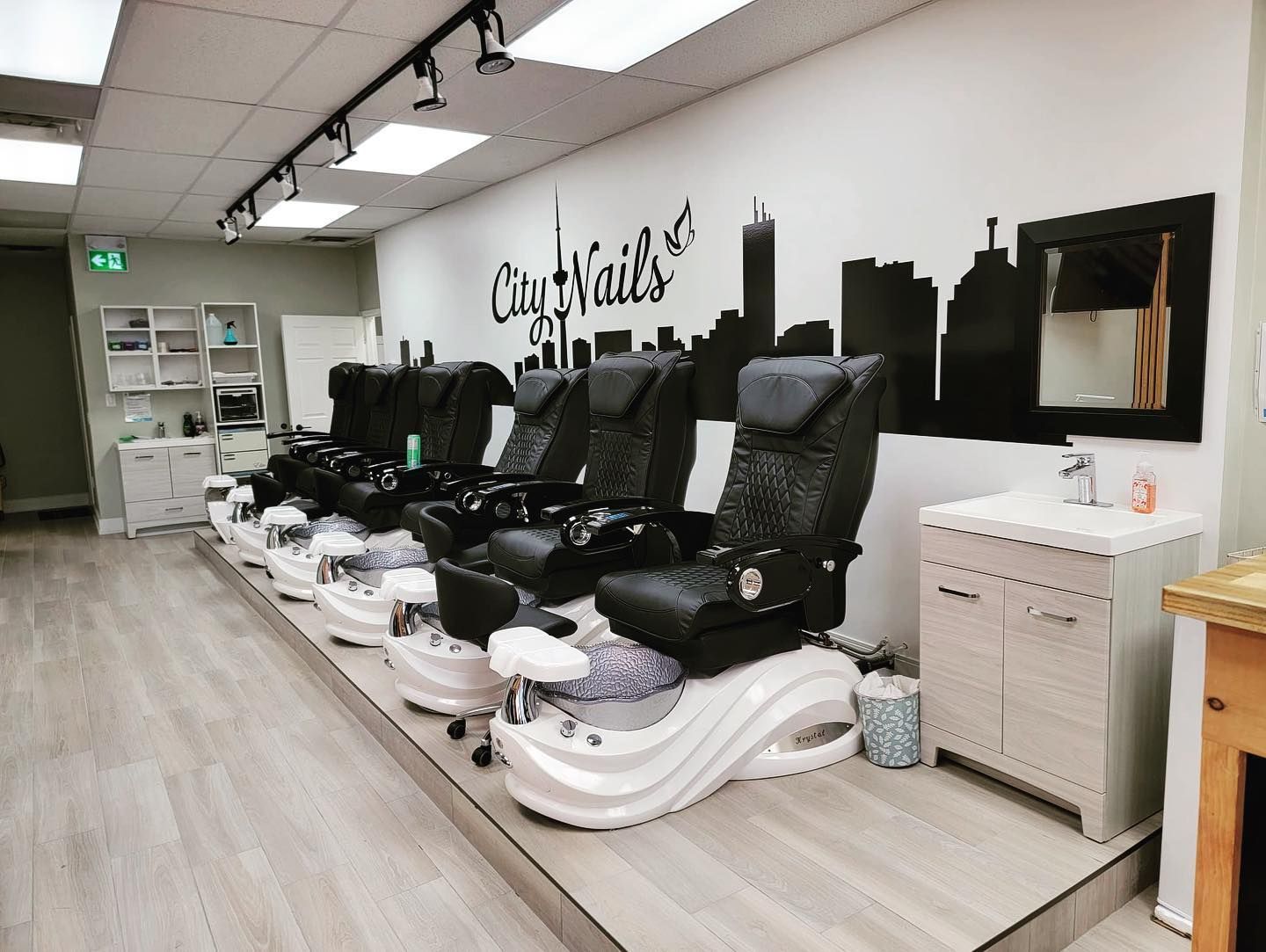 A row of nail salon chairs are lined up in a room.