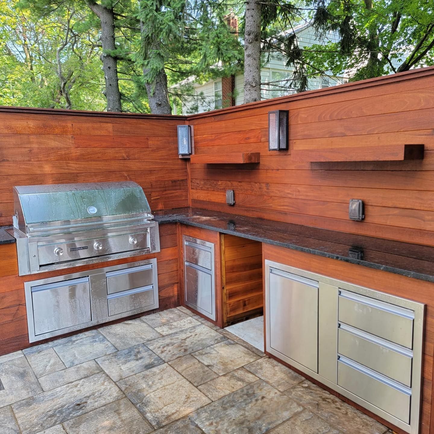 An outdoor kitchen with stainless steel cabinets and a grill